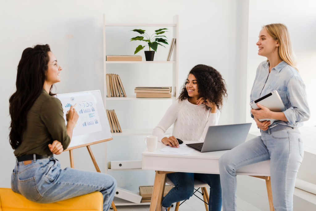 three women talking and a white board